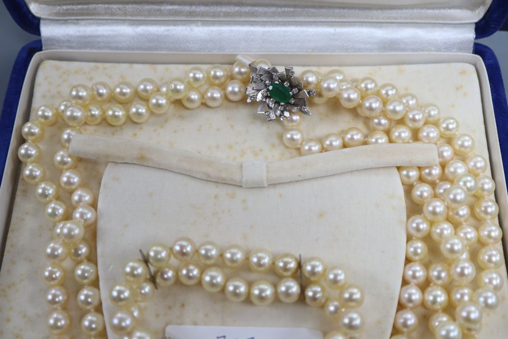 A triple strand cultured pearl necklace and matching bracelet with white metal, emerald and diamond set clasps & 1 other bracelet.